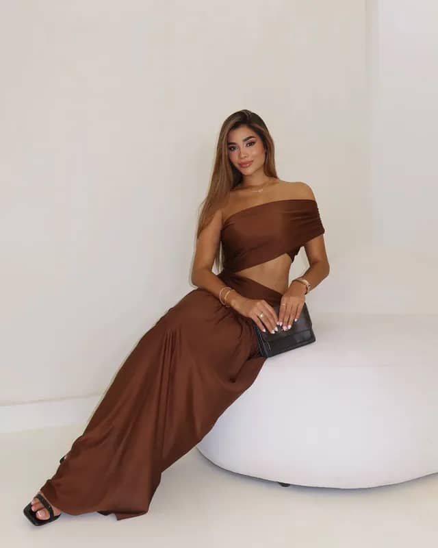 Modelo sentada con el Vestido Fantasía café: top drapeado a un hombro y abertura lateral