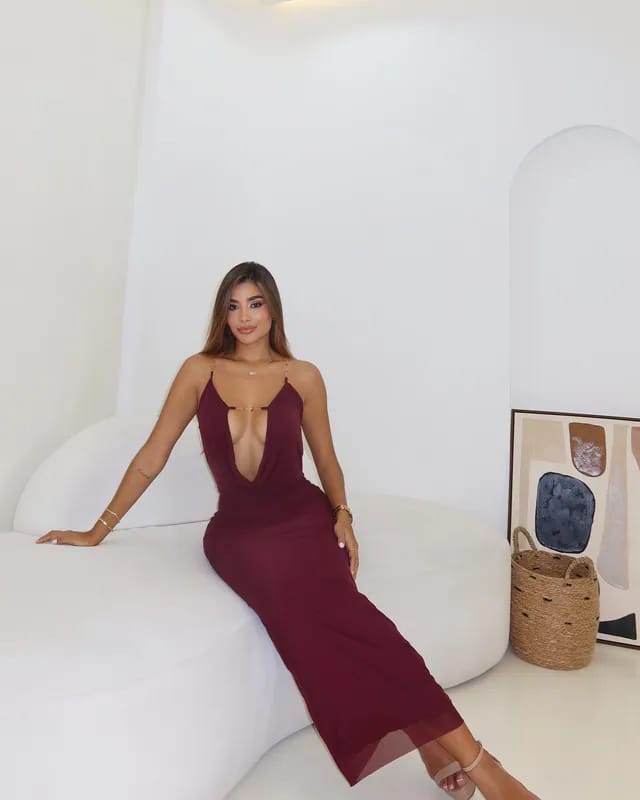 Modelo sentada luciendo el Vestido Flower vinotinto, maxi halter con escote en V profundo y tirantes de cadena dorada