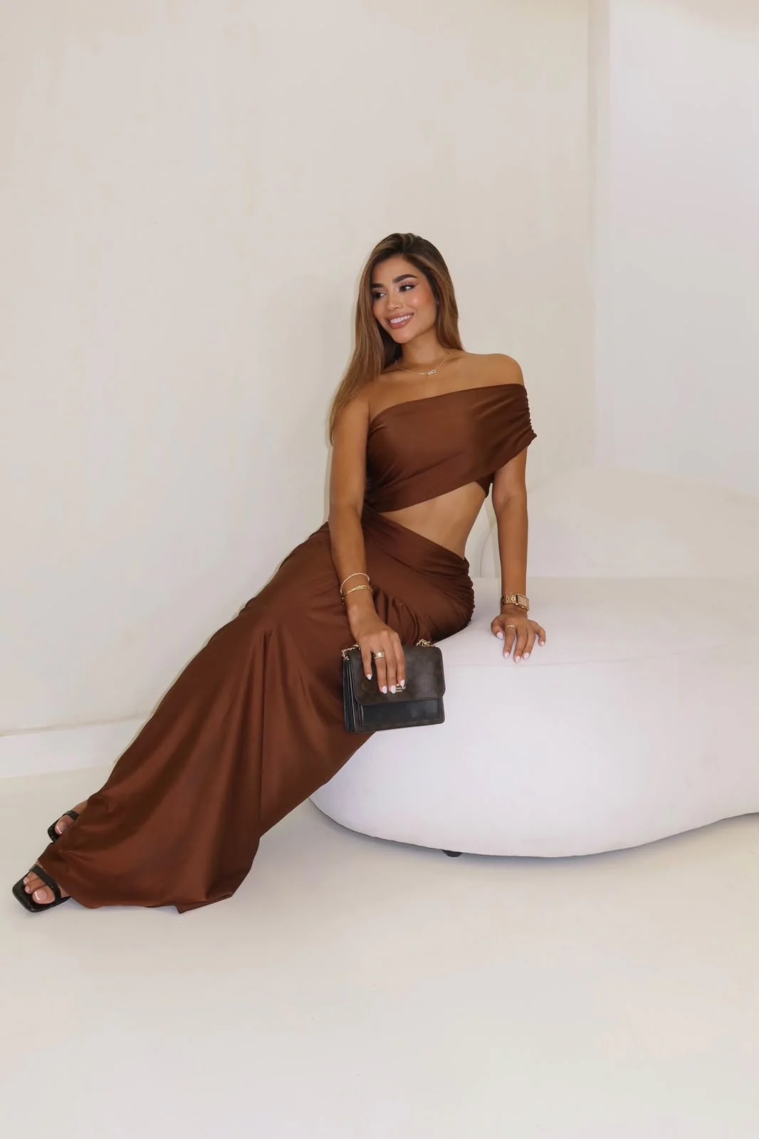 Vestido Fantasía café con falda maxi fruncida, modelo sentada sonriendo